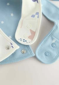 Prenda de color azul claro con interior crema, que presenta patrones de estrellas y bloques. Con botones de presión a lo largo de los bordes; textura de algodón suave.