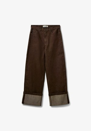 Jean marron à jambes larges avec revers aux ourlets montrant un tissu intérieur plus clair, bouton à l'avant et design cinq poches.