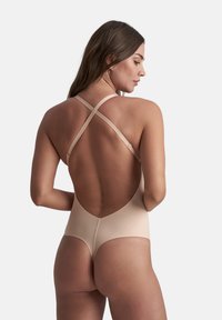 Costume da bagno beige con schiena bassa e spalline incrociate. Materiale liscio e elastico e design della parte inferiore con copertura media.
