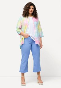 Ylihäivutettu, monivärinen t-paita pastellisävyissä, yhdistettynä vaaleansinisiin lyhytlahkeisiin housuihin ja vaaleisiin, nauhalla varustettuihin platform-sandaaleihin.