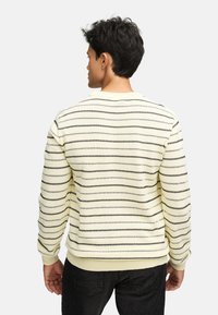 Stribet sweater i lys gul med sorte vandrette striber. Har ribbede manchetter og kant for et tætsiddende look. Blød tekstur, rund halsudskæring.