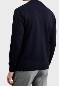 Navy blue knitted sweater with a round neckline and ribbed cuffs. Smooth texture, fitted silhouette, and solid color design.