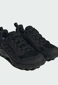 Zapatillas deportivas negras con parte superior de malla, acentos texturizados, sistema de cordones robusto y suela resistente para una mejor tracción.