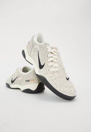 Para białych i szarych butów piłkarskich Nike Total 90 II z czarnymi logo Swoosh i czarnymi podeszwami na białym tle.