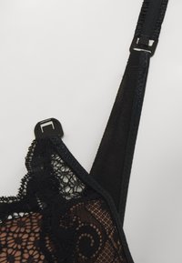 Sutiã de renda preta com padrões florais intricados, alças ajustáveis e um fecho de gancho e olho seguro. Construção em tecido de malha suave.