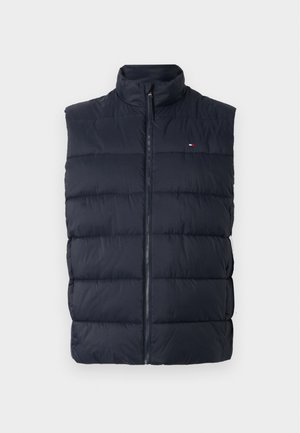 Gilet rembourré bleu marine foncé avec un col haut, une fermeture éclair et des sections matelassées horizontales pour l'isolation. Petit logo sur la poitrine.