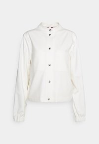 Veste blanche en tissu doux, avec un col montant, des boutons-pression, deux poches poitrine et des poignets élastiques.