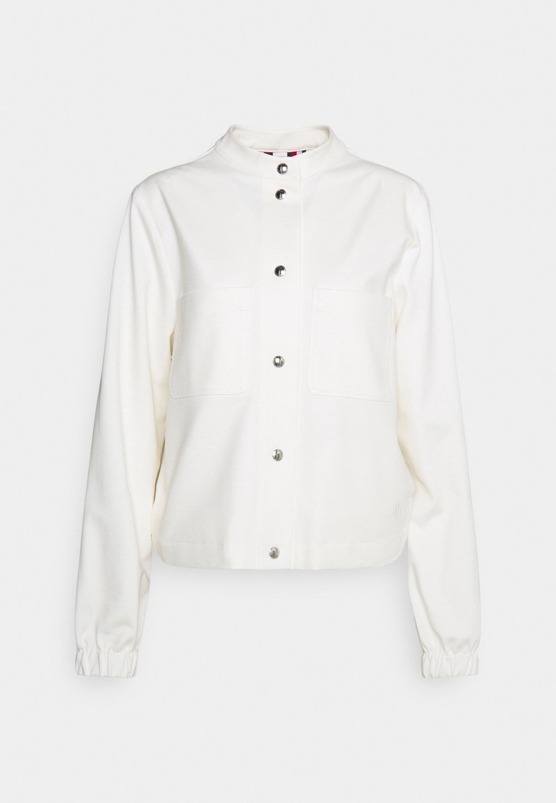 Veste blanche en tissu doux, avec un col montant, des boutons-pression, deux poches poitrine et des poignets élastiques.