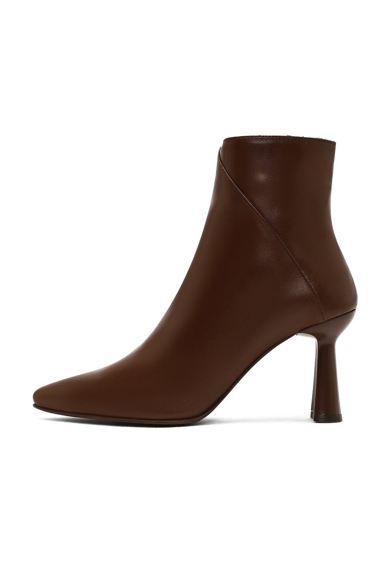 Bottine en cuir brun avec un bout pointu, au design épuré et à talon haut et fin. Texture lisse avec une finition sans couture.