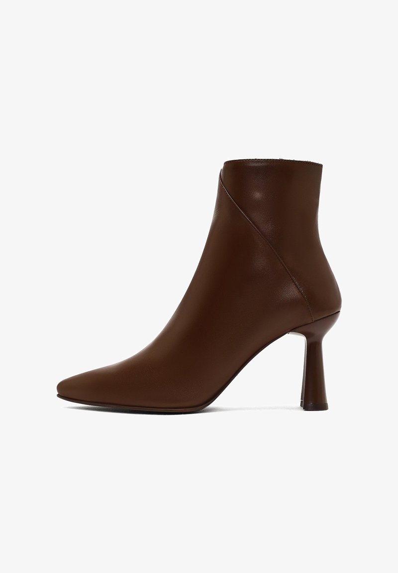 Bottine en cuir brun avec un bout pointu, au design épuré et à talon haut et fin. Texture lisse avec une finition sans couture.