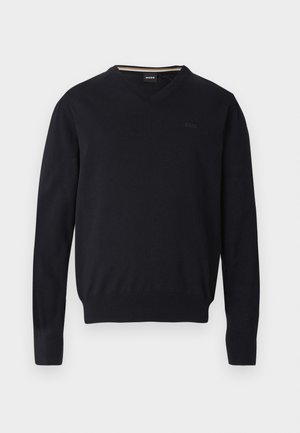 Svart v-hals genser laget av mykt strikket stoff. Har lange ermer, ribbede mansjetter og kant, med preget logodetalj på brystet.