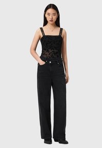 Schwarzer Spitzen-Body mit breiten Trägern und floralem Muster, kombiniert mit hoch taillierten schwarzen weit geschnittenen Jeans; schlanke und strukturierte Silhouette.