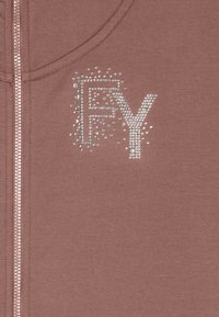 Sudadera con cremallera en color rosa empolvado, con diseño "FY" en pedrería. Textura de tela suave con detalle de cremallera metálica.