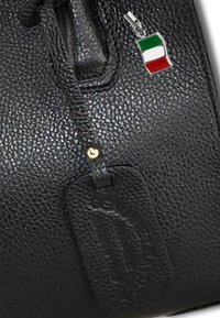 Zwarte leren tas met textuur, gouden hardware en een decoratieve hanger met de Italiaanse vlag in groen, wit en rood.