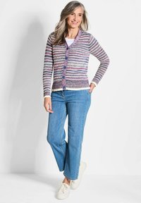 Gestreepte cardigan in paars, roze en wit, met een knopenfront, geribbelde zoom en lange mouwen, gecombineerd met lichtblauwe jeans en witte sneakers.