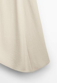 Lichtbeige rok van een gladde, gestructureerde stof. Heeft een vloeiende silhouet en een lichte uitloop aan de onderkant voor bewegingsvrijheid.