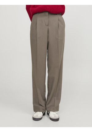 Personne portant un pantalon taupe taille haute à jambes larges, des baskets blanches et noires, et un pull rouge rentré dans le pantalon.