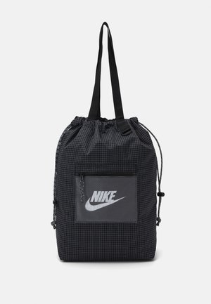 Sac à dos noir à cordon de serrage en matériau structuré avec un motif en grille, comportant une poche avant avec un logo Nike gris et des sangles noires.