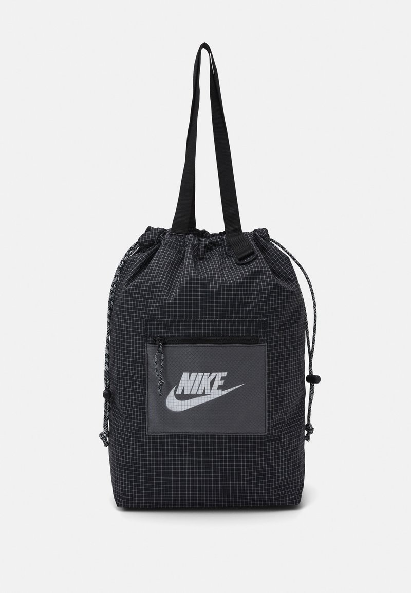 Sac à dos noir à cordon de serrage en matériau structuré avec un motif en grille, comportant une poche avant avec un logo Nike gris et des sangles noires.