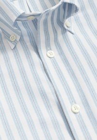 Lichtblauw-wit gestreept overhemd van geweven katoen. Voorzien van een button-down kraag en witte knopen met een gladde textuur.