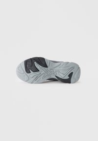 Shoe sole with a textured black and light gray pattern, featuring wave-like grooves and raised accents for traction and stability.