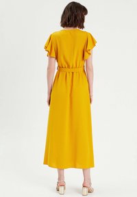 Yellow maxi dress with flutter sleeves and a belted waist. Smooth fabric, floor-length, and a straight cut. No visible patterns or accents.