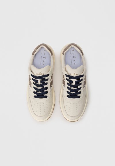 Fehér bőrsneaker kék fűzőkkel és barna részletekkel. Lyukacsos részletek az orr részen. Arany színű márkalog�ó az oldalon. Lapos gumitalp.