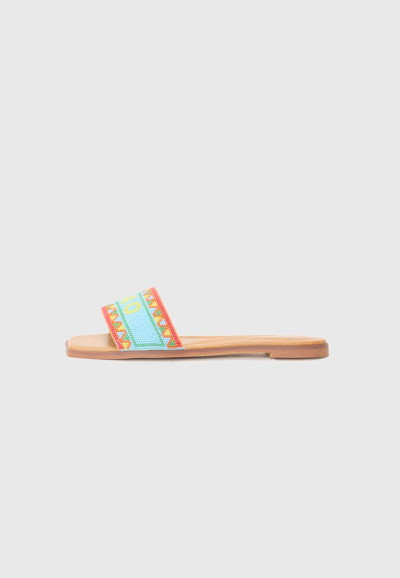 Sandale à enfiler avec une sangle tissée colorée présentant des motifs géométriques en bleu, rouge et jaune, accompagnée d'une semelle en faux cuir beige.