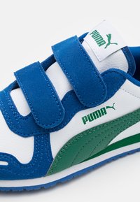 Baskets bleu et blanc en matériaux de daim et de cuir, dotées de straps Velcro, d'accents verts et d'un logo sur la languette.