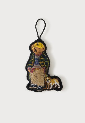 Porte-clés brodé représentant un ours portant une casquette jaune, une veste à carreaux verte, un pantalon beige et des baskets, debout à côté d'un petit chien marron et blanc.
