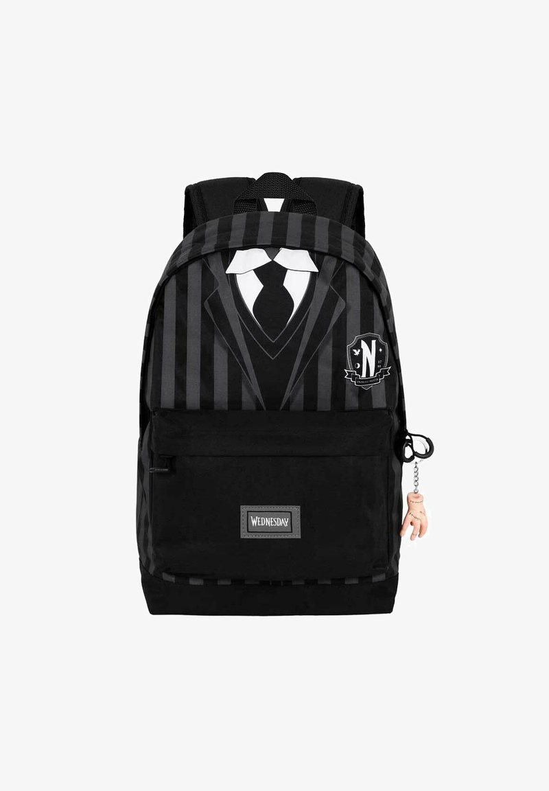 Sac à dos noir présentant un design de smoking avec des rayures, un patch avec la lettre 'N' et un petit charm en forme de main sur la fermeture éclair.