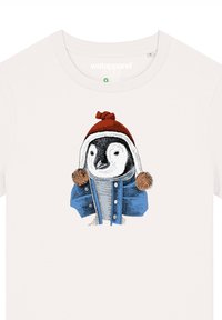 Witte t-shirt met een illustratie van een pinguïn in een blauwe jas met twee pompoenen en een rode hoed, met de nadruk op gedetailleerd lijnwerk en kleuren.