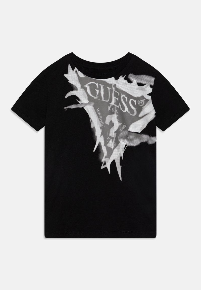 Musta puuvillapaita, jossa on suuri valkoinen graafinen printti "GUESS"-logosta, jossa on sahalaitaiset reunat ja tekstitietoja. Lyhyet hihat, pyöreä kaula-aukko.