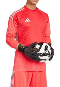 Rode sportshirt met lange mouwen en een gemêleerd patroon, gecombineerd met zwarte keepershandschoenen met gouden accenten, en houdt een zwart-wit voetbal vast.