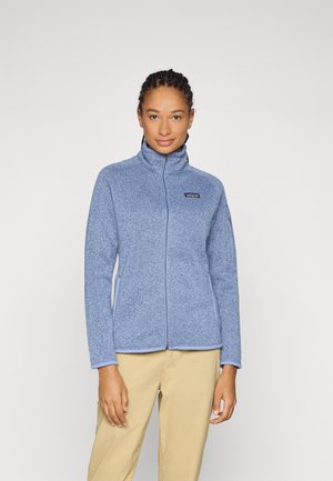 Lichtblauwe fleece jack met een hoge kraag, volledige rits en een logo patch op de borst. Glad textuur en een getailleerd ontwerp.