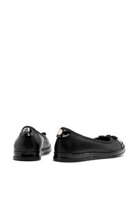 Czarne skórzane baleriny z błyszczącą patynową osłoną palców i detalem w postaci kokardki, posiadające metaliczny akcent na obcasie oraz przeszywaną podeszwę.