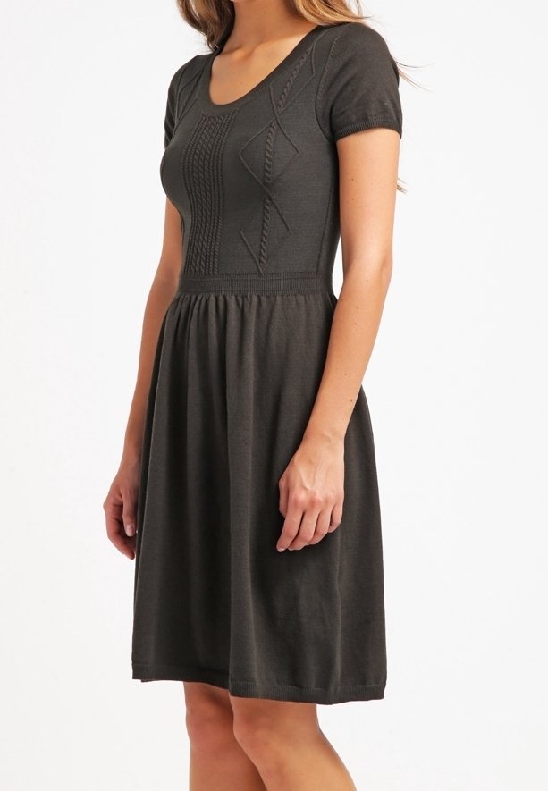 Femme portant une robe en maille gris foncé, manches courtes, longueur genou, avec des motifs torsadés texturés sur le corsage et une taille froncée.