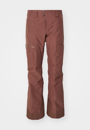 Barna vízálló sínadrág, laza szabású, cipzáras zsebekkel és strukturált mandzsettával. Simább külső felülettel és tartós anyagból készült.