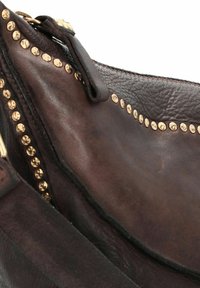 Braune Lederhandtasche mit strukturiertem Oberflächen, die goldene Nietenverzierungen entlang der Kante und einen Reißverschluss besitzt.