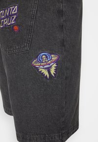 Svarte denimshorts med fargerike broderte detaljer: "SANTA CRUZ"-logo og en UFO med en alien. Teksturert stoff med klassisk snitt.