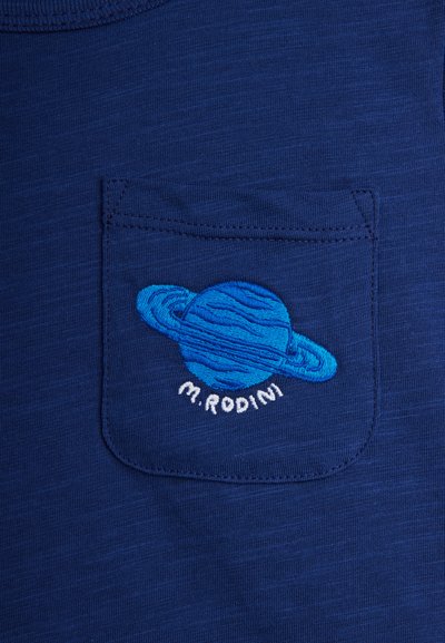 Μπλε υφασμάτινη τσέπη με κεντημένο μπλε πλανήτη με δακτυλίους και το κείμενο "M.RODINI" κάτω από τον πλανήτη.