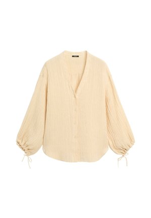 Blusa beige a maniche lunghe con scollo a V, chiusura con bottoni sul davanti, tessuto strutturato e maniche raccolte legate con piccoli fiocchi ai polsi.