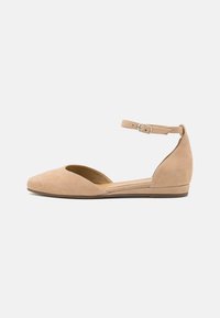 Ballerines en suède beige avec un bout arrondi, des côtés ouverts et une sangle à la cheville avec une boucle. Dotées d'un talon bas et d'une doublure intérieure lisse.