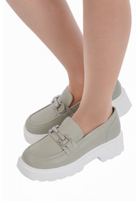 Ljusgröna syntetiska loafers med en kraftig vit sula och silverkedjedetalj, med en jämn textur och rund tådesign.