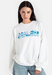 Biała, przesadnie duża bluza z okrągłym dekoltem, z niebieskim graficznym napisem "COLOR" w kwiatowym stylu. Miękka tkanina i ściągacze przy rękawach.