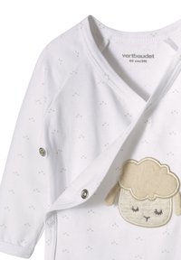 Weißer Baumwoll-Overall mit kleinen beige Punkten, der ein cremefarbenes Schaf-Applikation auf der Brust hat und seitliche Druckknöpfe bietet.