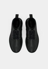 Cizme negre din piele, până la glezne, cu o textură netedă, vârf rotund, design cu șireturi și tab pentru a le trage pe călcâi. Stil minimalist, fără accente suplimentare.