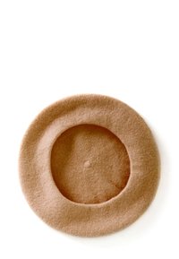 Cappello rotondo realizzato in morbido feltro marrone, caratterizzato da una superficie liscia e una depressione centrale. I bordi sono leggermente sollevati, creando una forma definita.