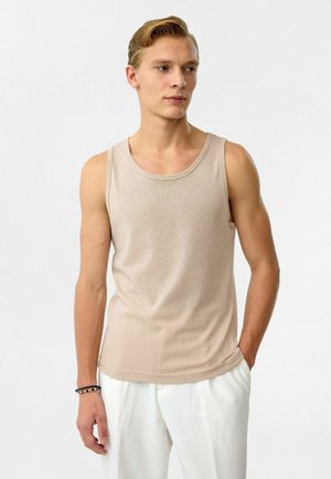 Beige geribbelde tanktop met een ronde halslijn en smalle bandjes, gecombineerd met witte plooirokken. Gladde textuur, casual pasvorm.