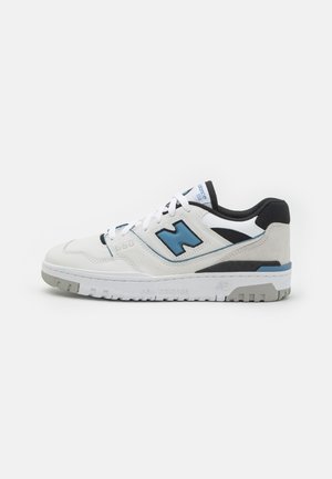 Sneaker bianco con accenti blu e neri, pannelli in pelle testurizzata e suede, lacci piatti e suola in gomma grigia. Presenta il marchio "New Balance".
